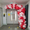 Organic Demi Arch: Latex balloon in Pink and red and white in various sizes, set in a hallway around the door frame.