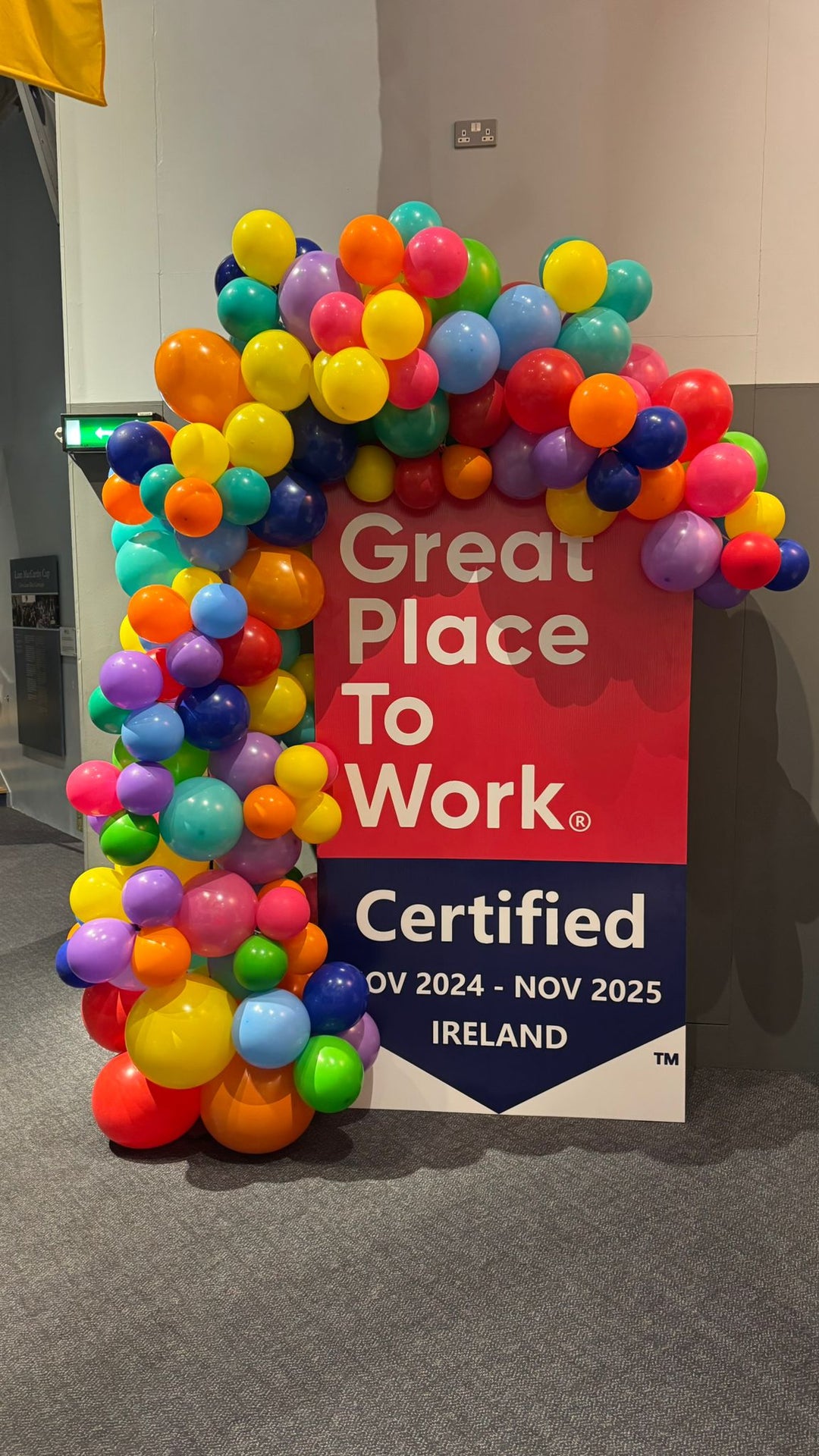 Organic Demi Arch: Latex balloon in rainbow colours in various sizes, Balloons going around a air board sign promoting an event.